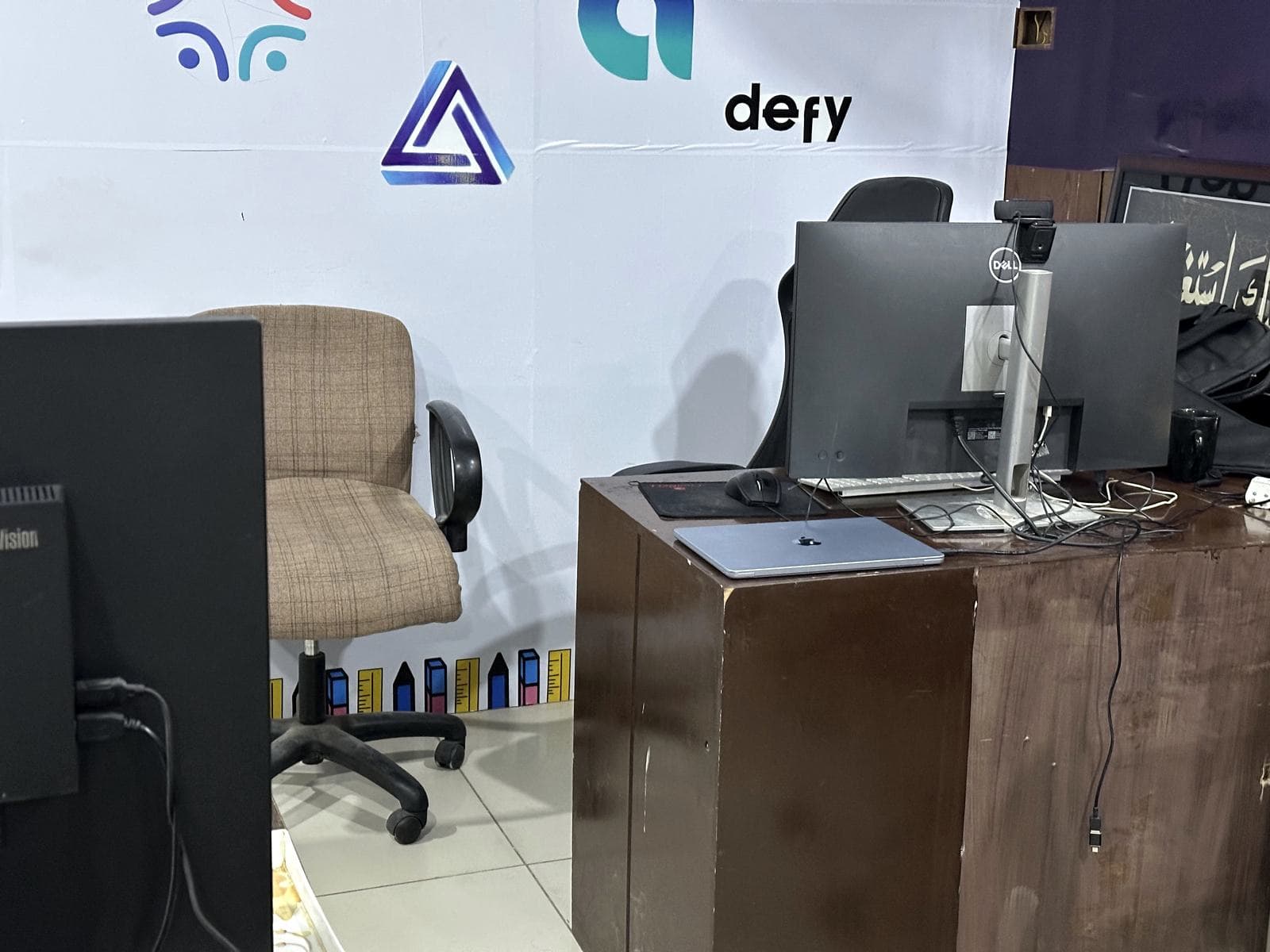 A workstation and a wall of client marks in the office.