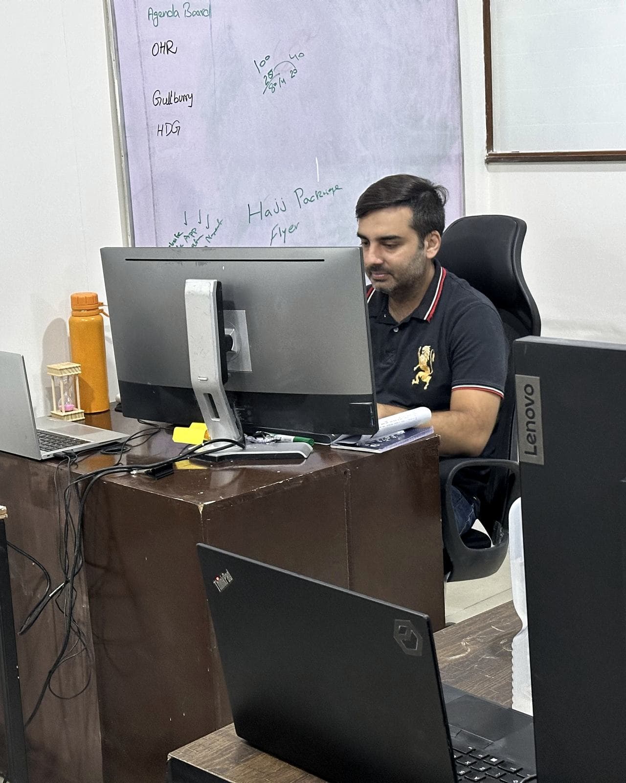 A person working at a desk in the 02X office, whiteboard with live jobs behind them.